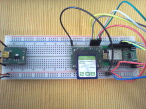 Links ein Anschluß für 5V USB-Spannungszufuhr mit 3,3V Regler. Mitte SD-Karte. Rechts das ESP-12F Modul mit Stapelheader. Vom USB-Spannungsanschluß werden die 5V an das ESP-Modul und an das SD-Karten-Modul weitergereicht. Das SD-Karten-Modul hat einen eingebauten 3,3V-Regler und einen Levelshifter. Damit kann es 5V- als auch 3,3V-Level verarbeiten.